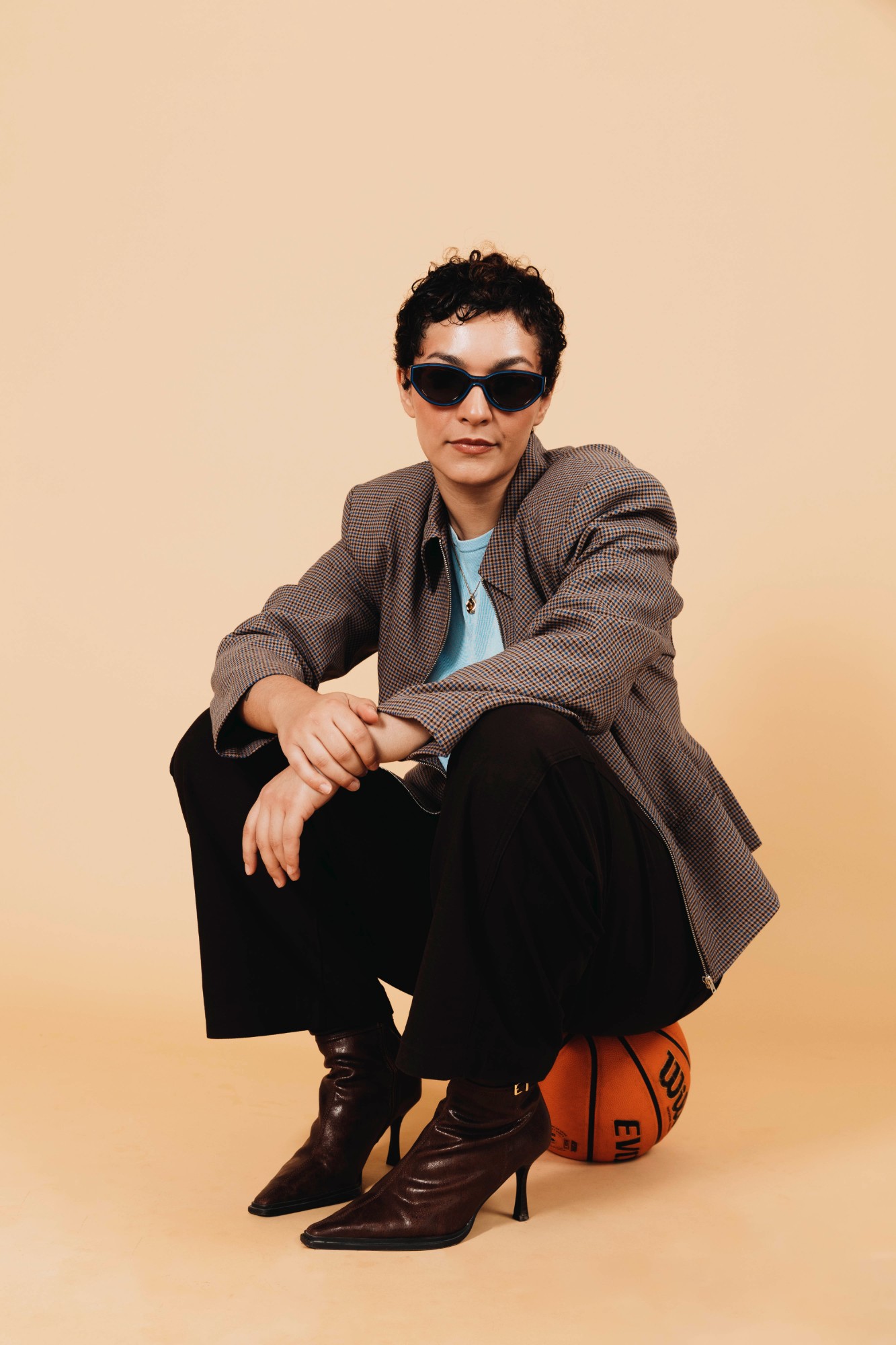 Loni Segoviano, founder of Off The Dribble, sitting on a basketball